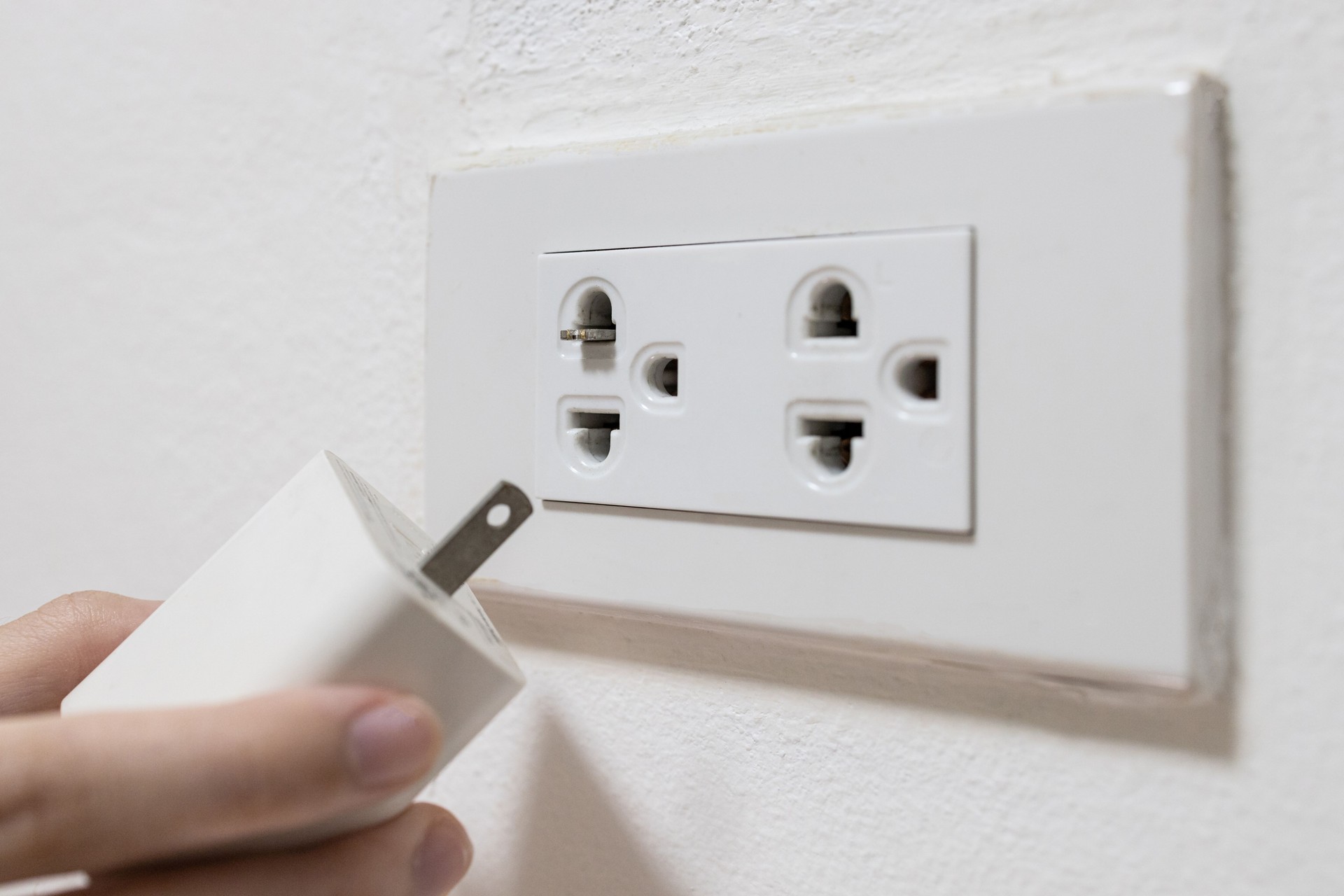 Broken pin contacts of electric plug,phone charger adapter pin is broken in the hole of power socket outlet,Damaged electrical,do not use hands directly to remove object from the hole of power outlet